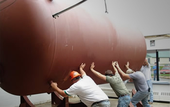 men pushing tank into place